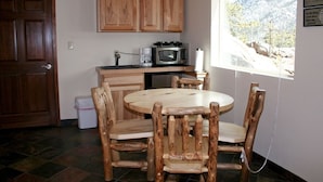 Une cuisine avec des meubles de rangement en bois, un four à micro-ondes, une machine à café et une table à manger avec des chaises en bois.