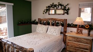 Une chambre avec une tête de lit en bois rustique, une couvre-lit blanche matelassée, une table de chevet avec une lampe et un miroir au-dessus du lit.