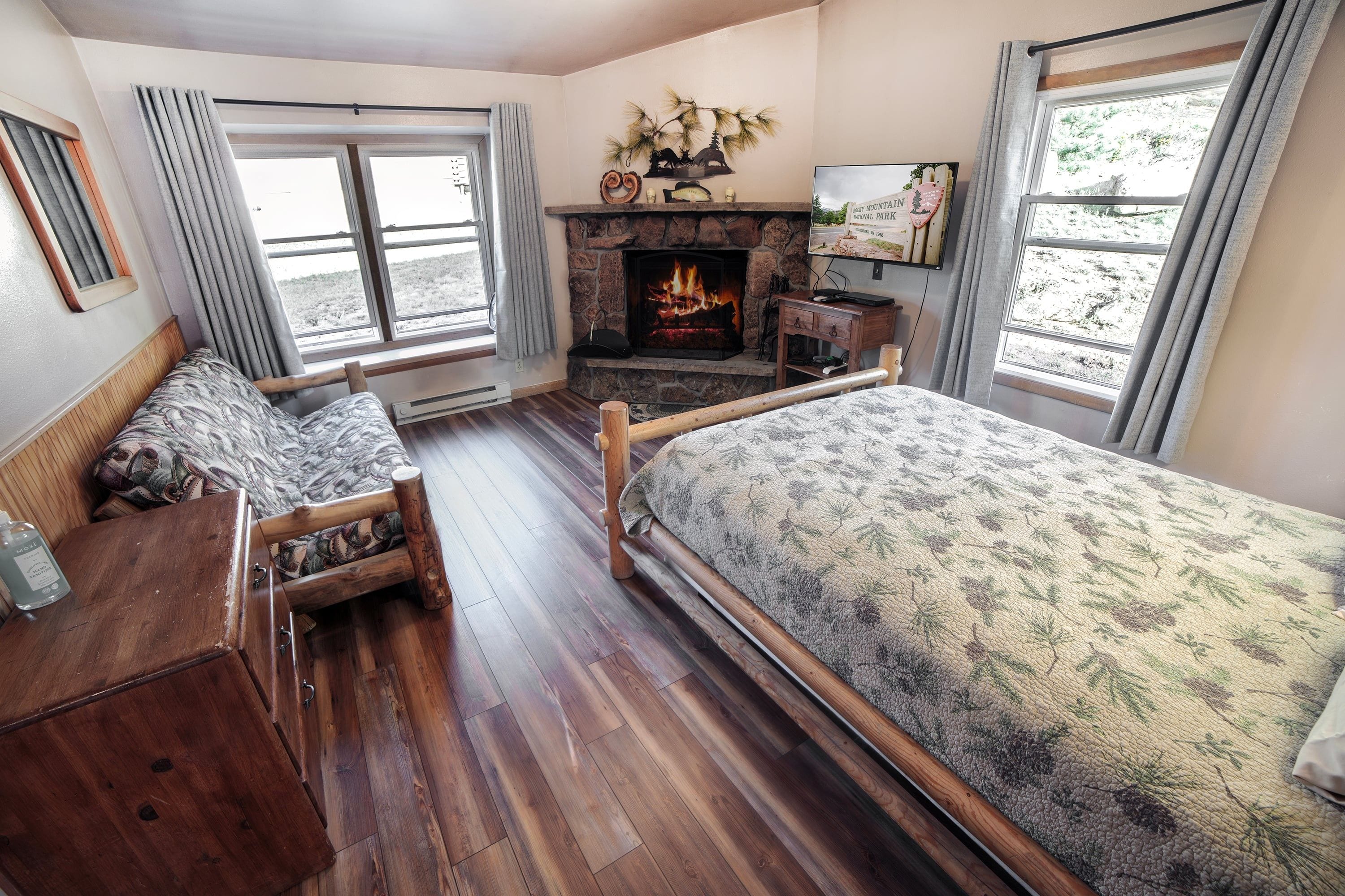 A cozy room with a fireplace, a bed, a desk, and a window with a view.