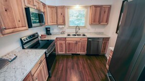 A compact kitchen with wooden cabinets, a black stove, a sink, and a dishwasher. - Fawn Valley Inn: 276 2 Bedroom Condo (Estes Park)