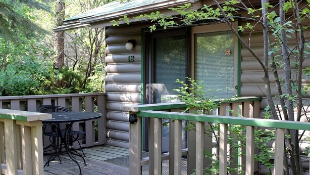 A log cabin with a deck, a table, and chairs. - Sunnyside Knoll: 12 1 Bedroom Apts (Estes Park)