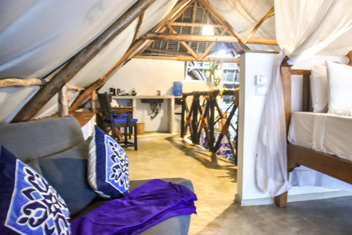 A tented accommodation with a bed, a chair, and a desk.