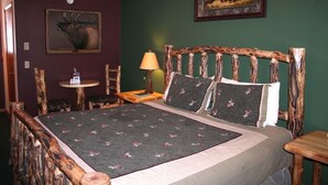 Une chambre à coucher avec une tête de lit en bois, une couvre-lit à motifs floraux et une petite table avec une lampe.