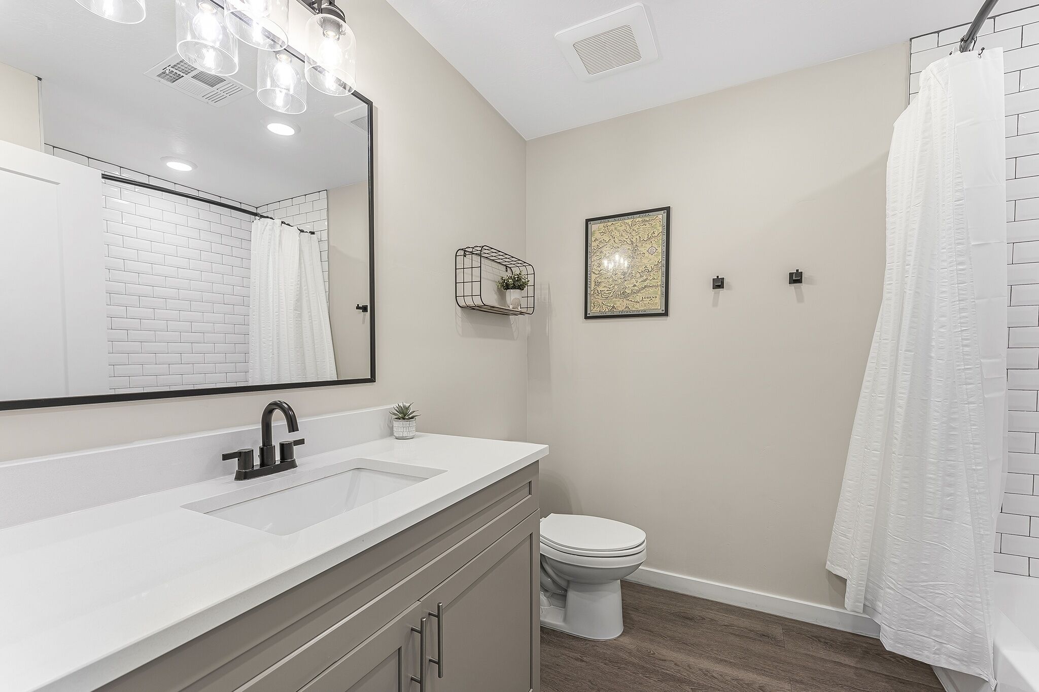 A modern bathroom with a white sink, a toilet, and a shower curtain.
