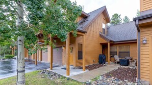 Ein zweistöckiges Haus mit überdachter Veranda, Garage und einer Terrasse mit Sitzgelegenheit im Freien.