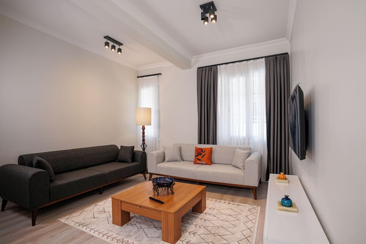 A modern living room with two sofas, a coffee table, a lamp, and a flat-screen TV mounted on the wall.