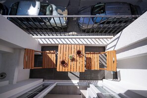 A balcony with a wooden table and chairs, a metal railing, and a view of parked cars. - Merkuri Apart (Istanbul)