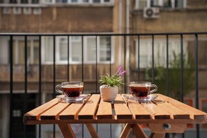 A wooden table with two cups of tea and a small potted plant on a balcony. - Merkuri Apart (Istanbul)