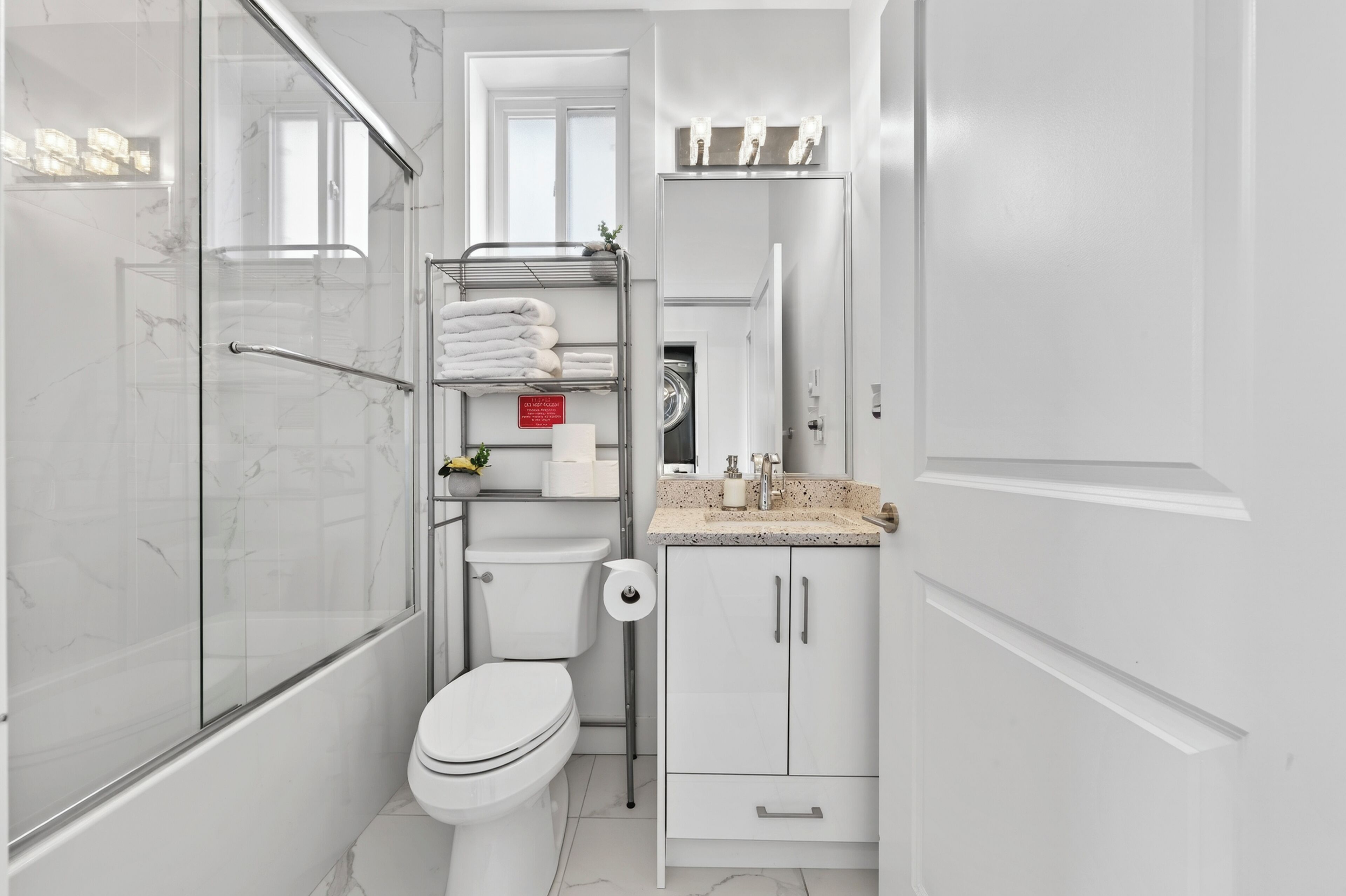 Un bagno moderno con box doccia in vetro, un water, un lavandino con piano e un mobile contenitore con specchio.