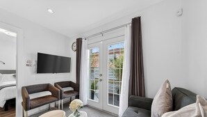 Ein modernes Wohnzimmer mit Sofa, Sitzbank, Wand-Fernseher und einer Schiebeglastür zum Außenbereich.