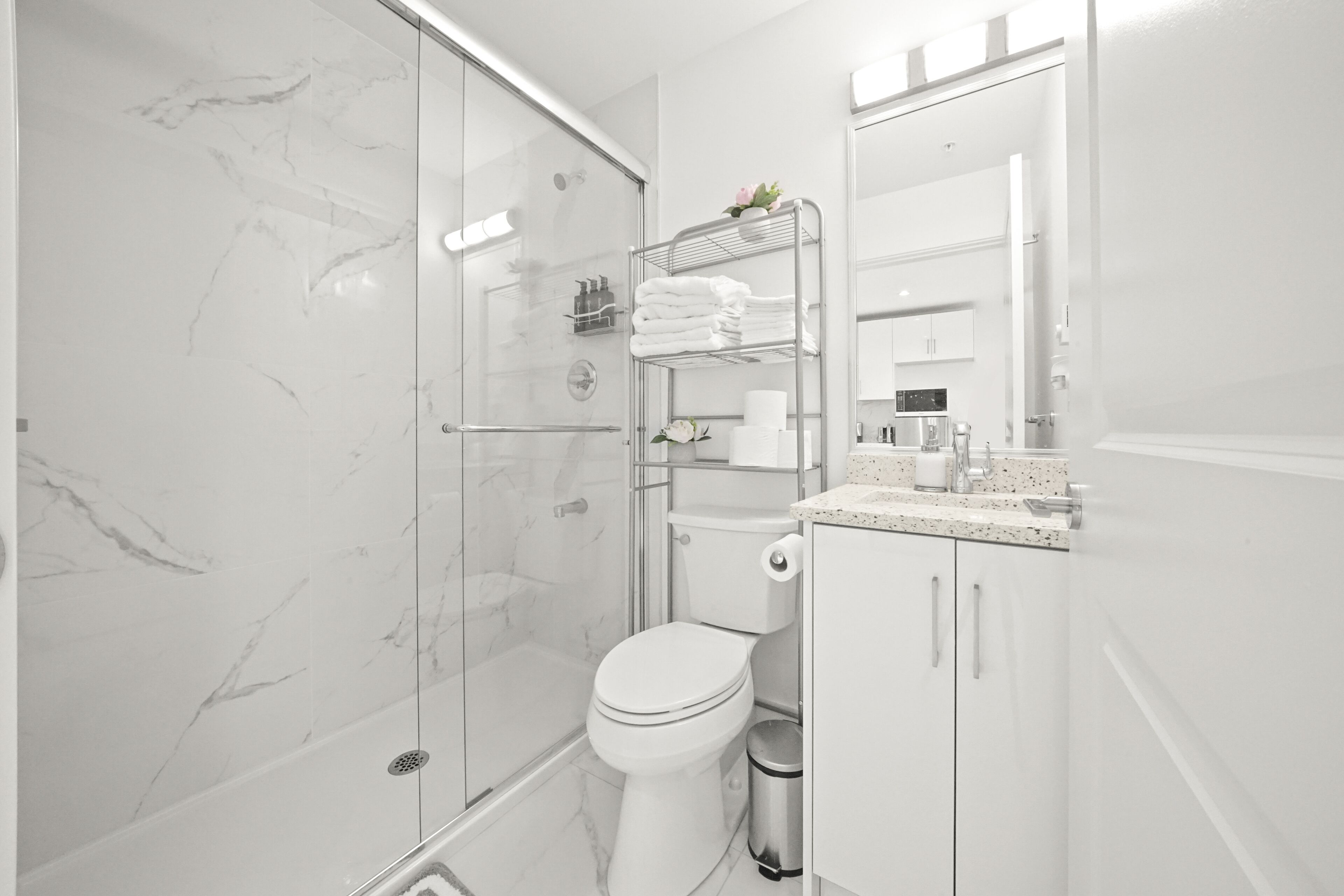 A modern bathroom with a glass-enclosed shower, a toilet, and a sink area with a countertop.