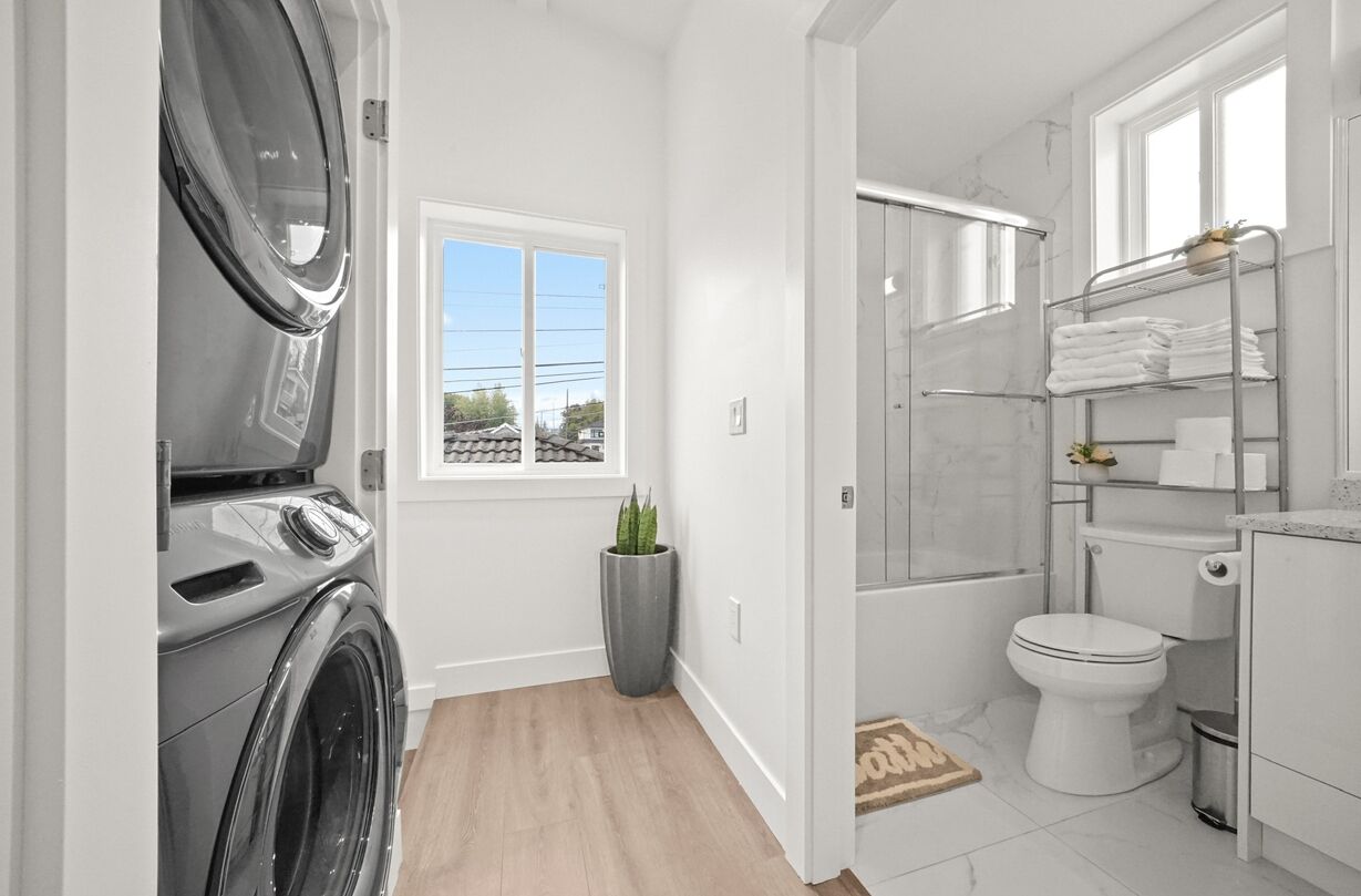 Une salle de bain moderne équipée d’un lave-linge, d’une douche et de toilettes.