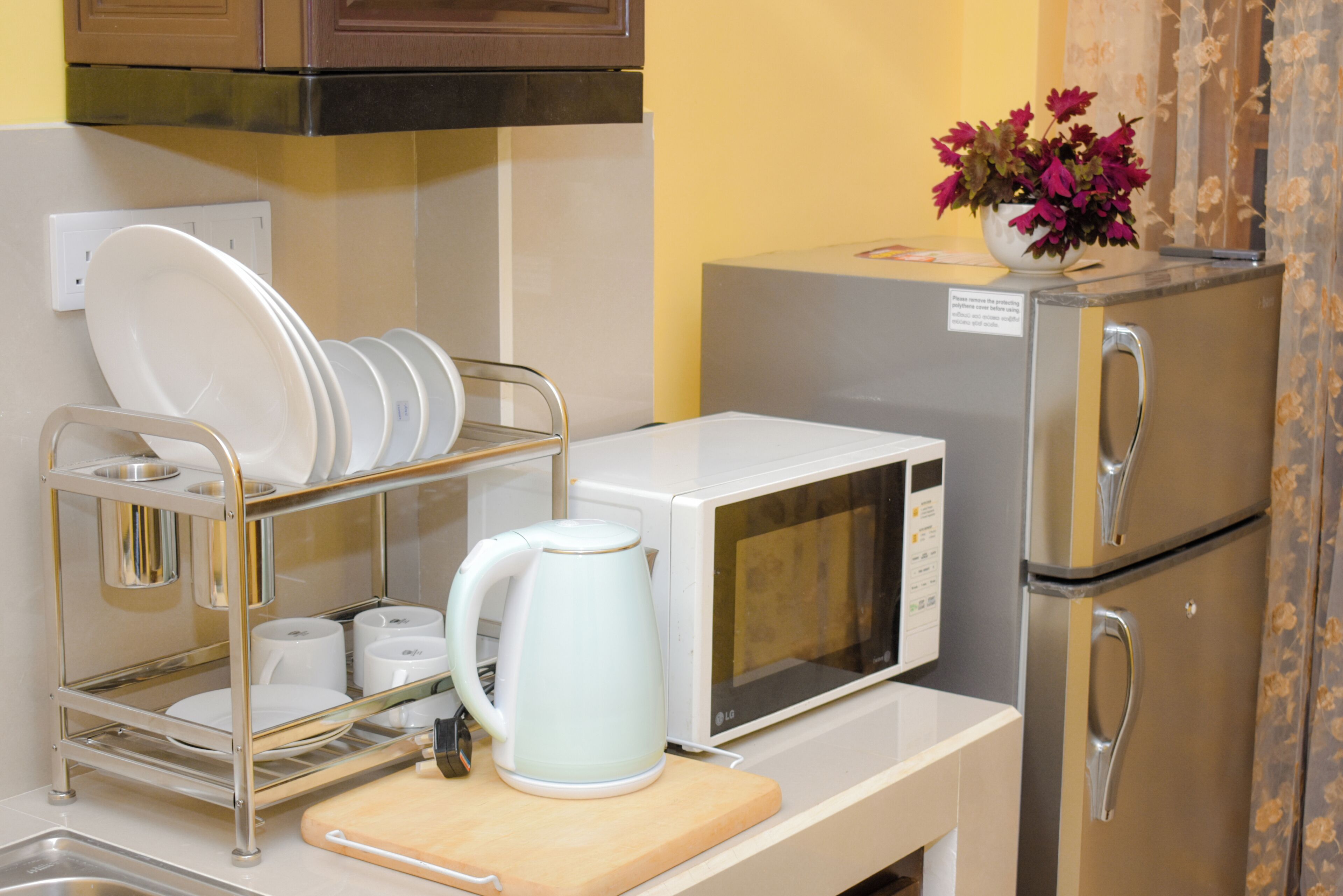 Cocina compacta con microondas, hervidor y escurreplatos.