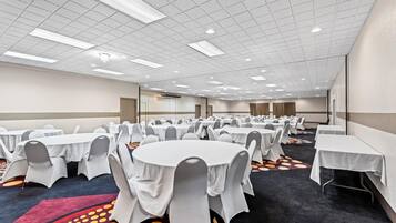 A conference room with round tables and chairs, a patterned carpet, and a ceiling with recessed lighting.
