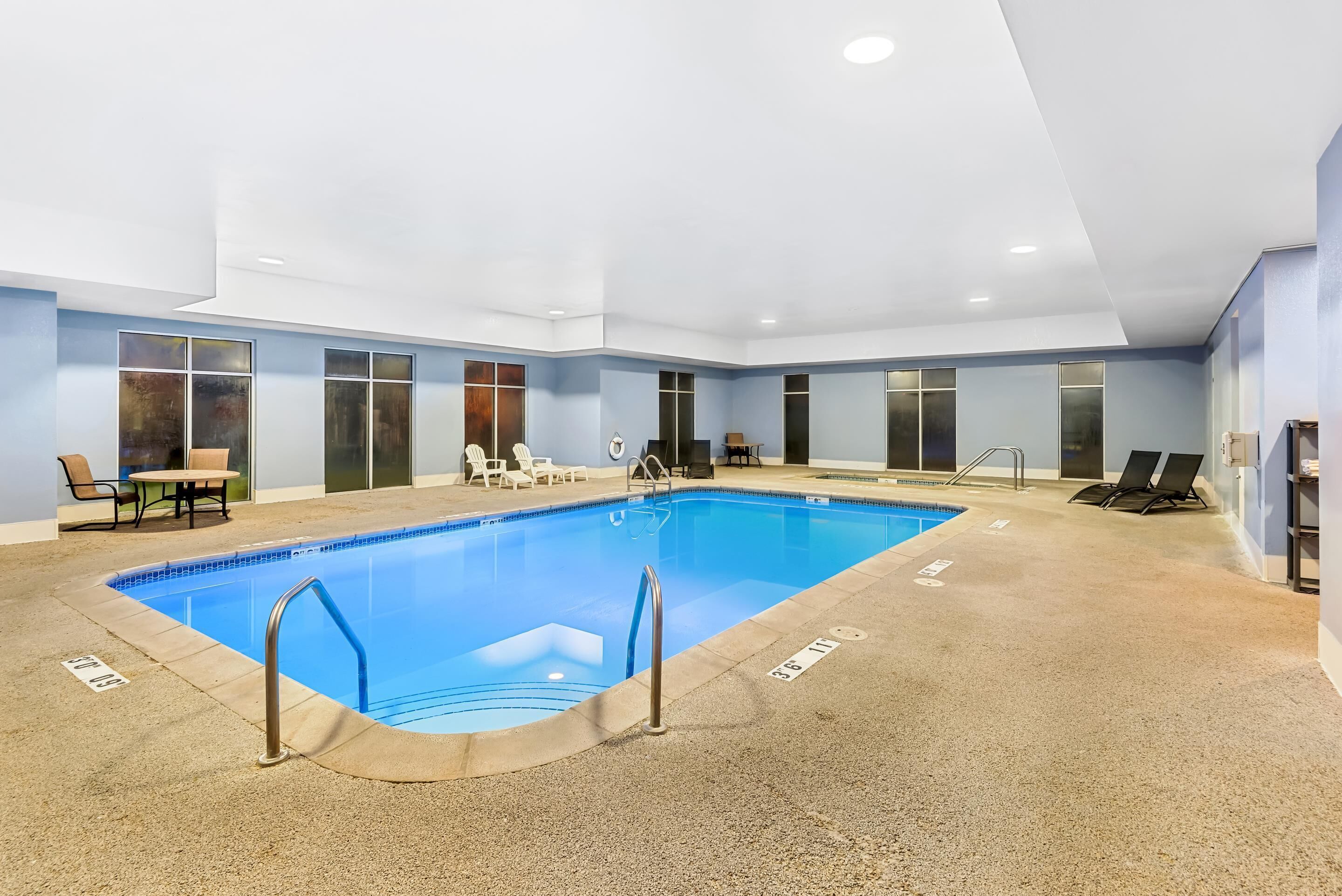Une piscine intérieure avec des lignes de démarcation bien visibles, des chaises longues et un espace dédié aux bains de soleil.