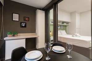 A hotel room with a dining area, a bed, and a small kitchenette. - Studios Hub Vila Madalena 2.0 (São Paulo)