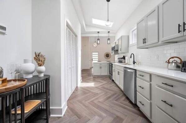 Modern kitchen with a central island, white cabinetry, and herringbone-patterned floor.