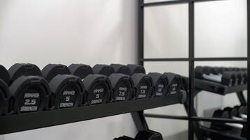 A rack of dumbbells with varying weights labeled from 2.5 to 10 strength.