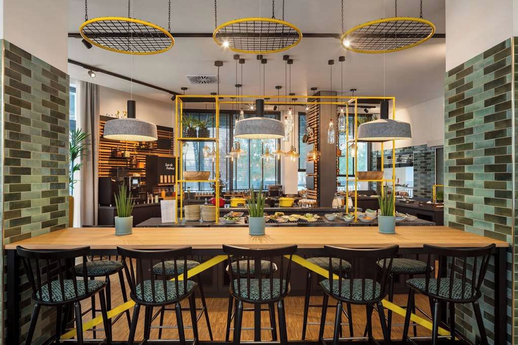 Un'area pranzo moderna con un tavolo lungo, diverse sedie, lampade a sospensione e una parete con decorazione a mattoni.