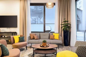 Una sala de estar moderna con un sofá, sillones, una mesa de centro y un televisor.