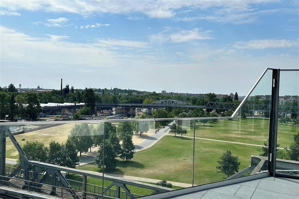 Une vue depuis un immeuble de grande hauteur, donnant sur un stade, un pont et un parc arboré.