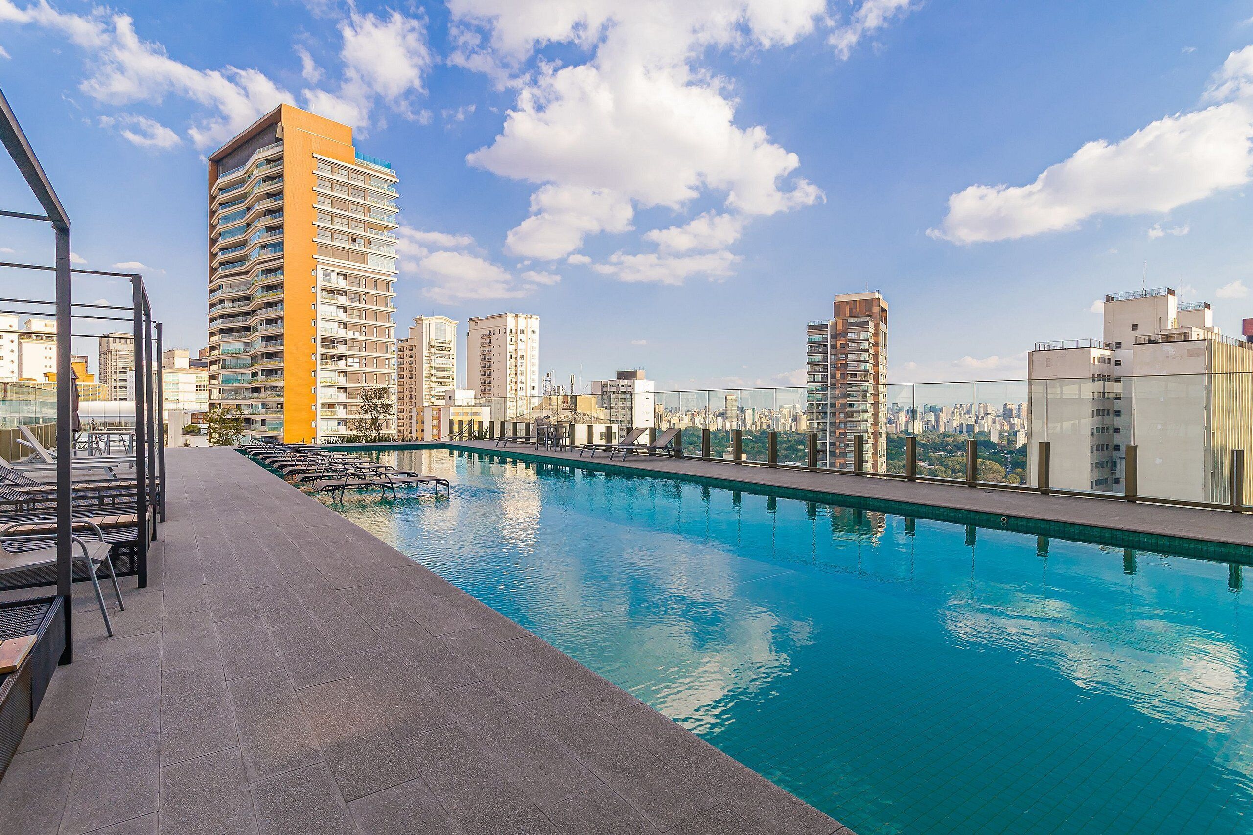A rooftop swimming pool with a cityscape view, surrounded by high-rise buildings.