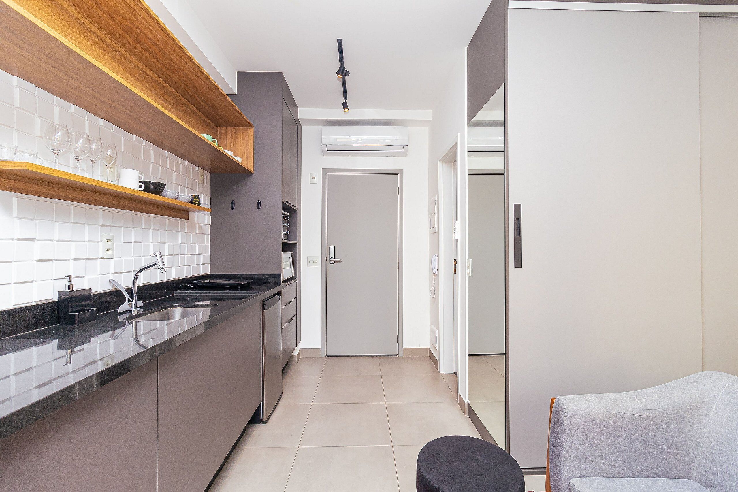 Una cocina moderna con encimera negra, electrodomésticos de acero inoxidable y estantes de madera.