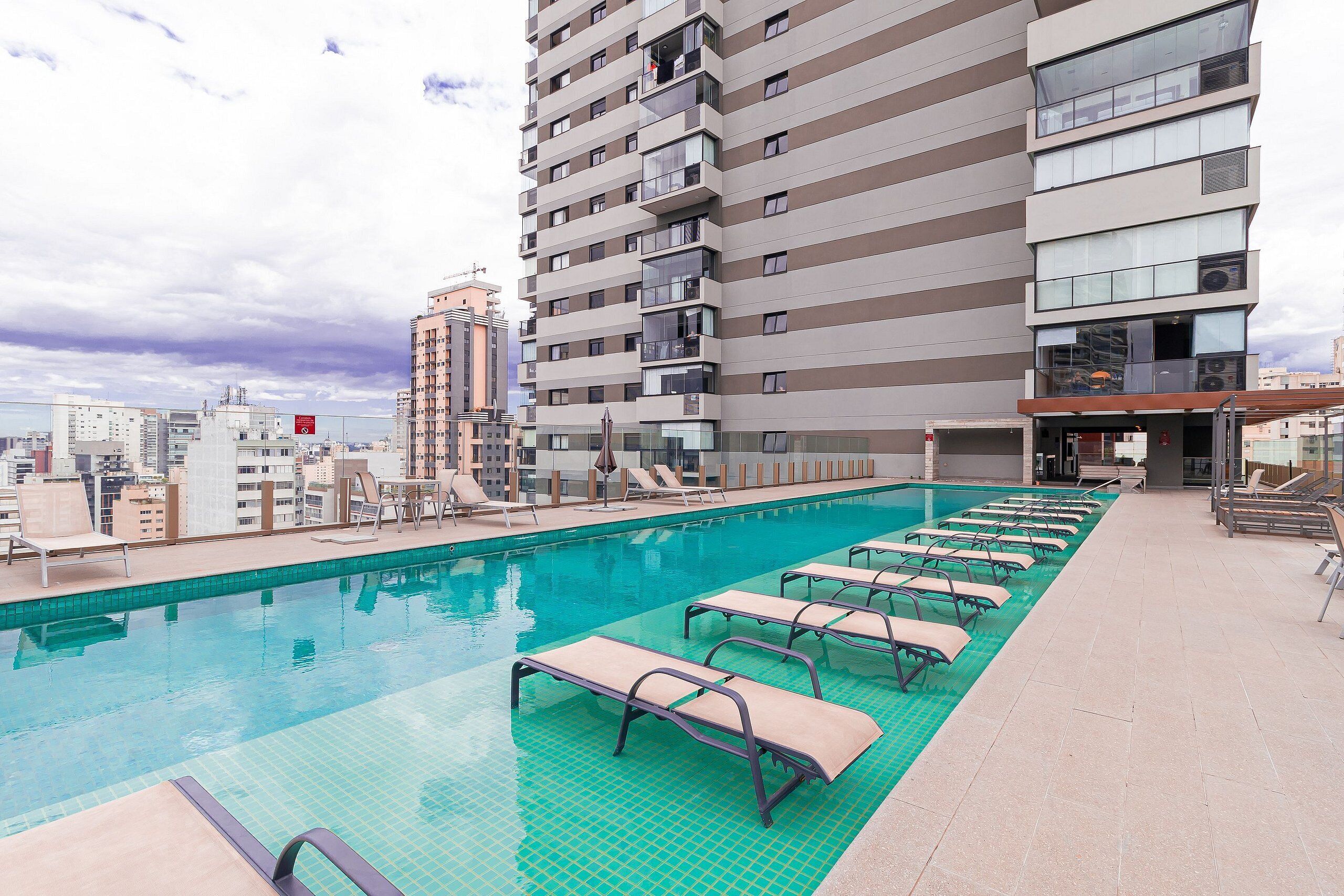 Ein Pool auf dem Dach mit Liegestühlen und Blick auf die Stadt.
