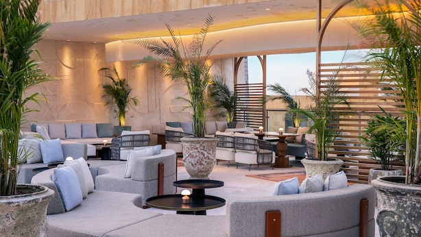 A modern lounge area with a circular seating arrangement, large planters, and a staircase in the background. - The St. Regis Riyadh (Riyadh)