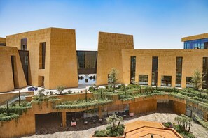 A modern building with a courtyard featuring outdoor seating and greenery.