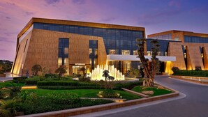 A modern building with a glass facade, a landscaped garden with a water feature, and the name "STREGIS" visible on the entrance. - The St. Regis Riyadh (Riyadh)