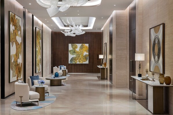 A modern hotel lobby with a long corridor, seating areas, and artwork on the walls.