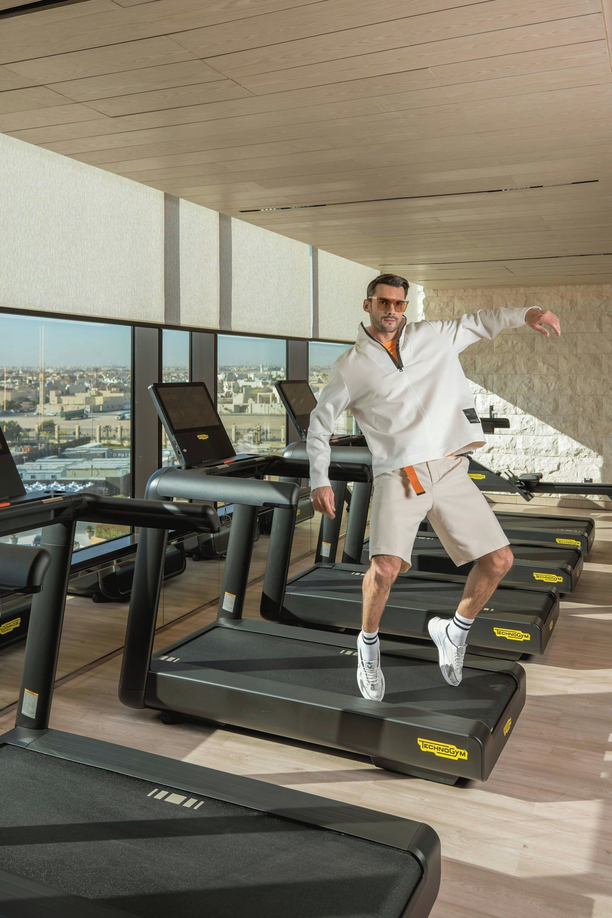 A gym with treadmills, a city view, and a modern interior design.
