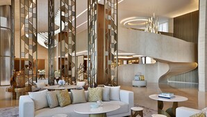 A spacious lobby with a modern staircase, a sofa set, and round tables. - The St. Regis Riyadh (Riyadh)