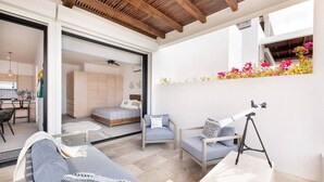 A modern living space with a sofa, chairs, a telescope, and a balcony with flowers.