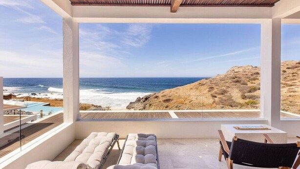 A balcony with a view of the ocean and a pool.