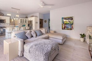 A modern living room with a sectional sofa, a fluffy throw blanket, and a contemporary painting on the wall. - Modern Cerritos Home • Walk to Beach & Dining (El Pescadero)