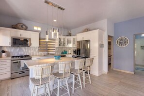Una cucina moderna con isola centrale, elettrodomestici in acciaio inossidabile e sgabelli da bar.