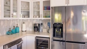 A kitchen with white cabinets, a stainless steel refrigerator, a coffee maker, and a water dispenser.