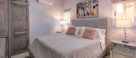 Un dormitorio con una cama grande, una mesita de noche, un tocador y un armario.