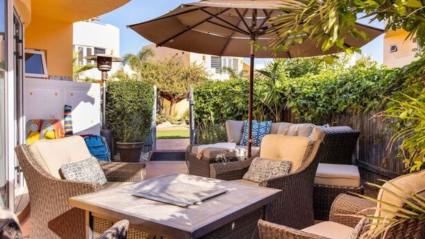 An outdoor patio with wicker furniture, a table, and an umbrella.