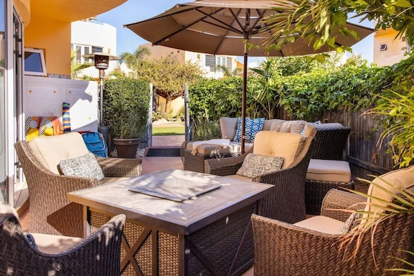 Une terrasse extérieure aménagée avec des meubles en osier, une table et un parasol.