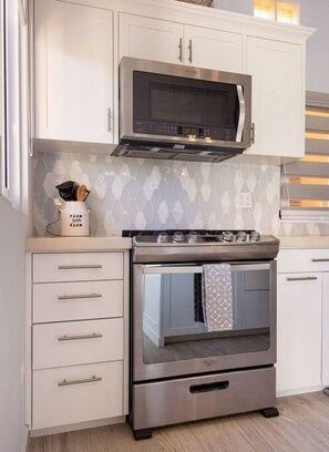 A kitchen with white cabinets, a stainless steel oven, and a microwave. - Modern Cerritos Home • Walk to Beach & Dining (El Pescadero)