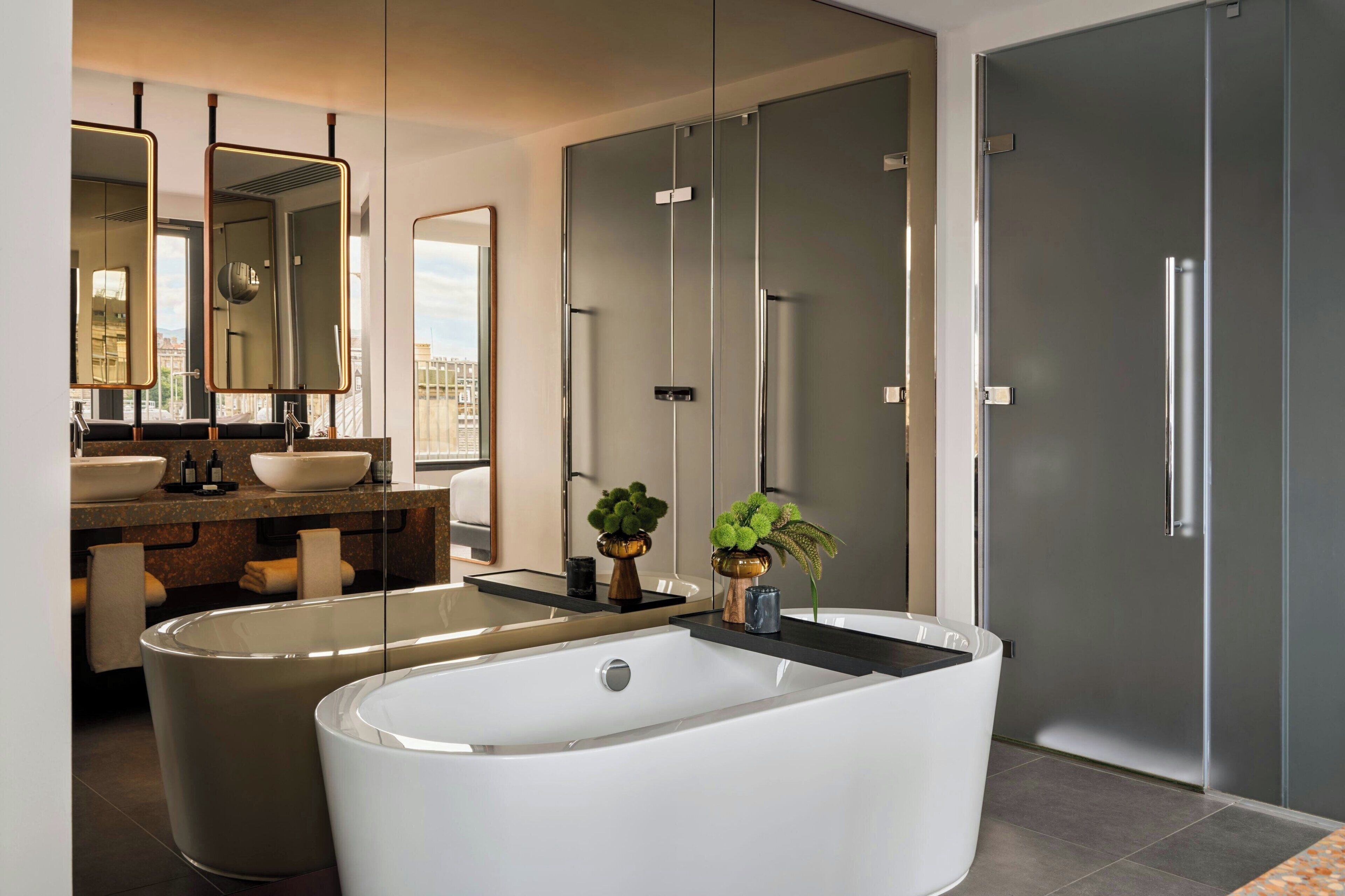 A modern bathroom with a freestanding bathtub, a double sink vanity, and a large mirror.