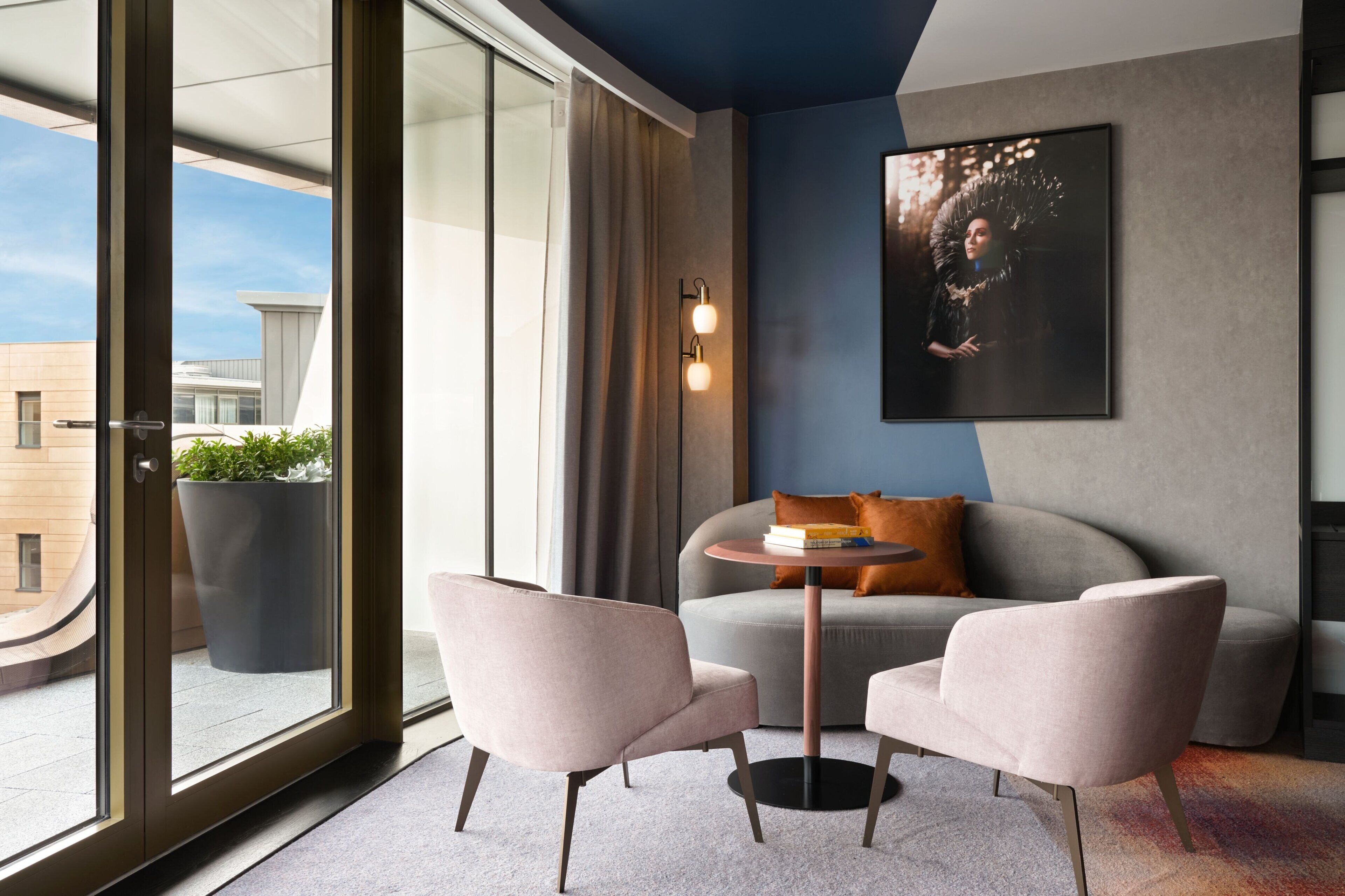 Ein modernes Wohnzimmer mit einer Couch, zwei Sesseln, einem Couchtisch und einem großen Fenster mit Blick auf Gebäude.