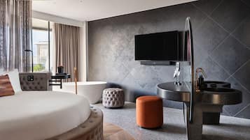 Una habitación de hotel moderna con una cama grande, un televisor de pantalla plana montado en la pared, una mesa de centro redonda y un diseño de lavabo original.
