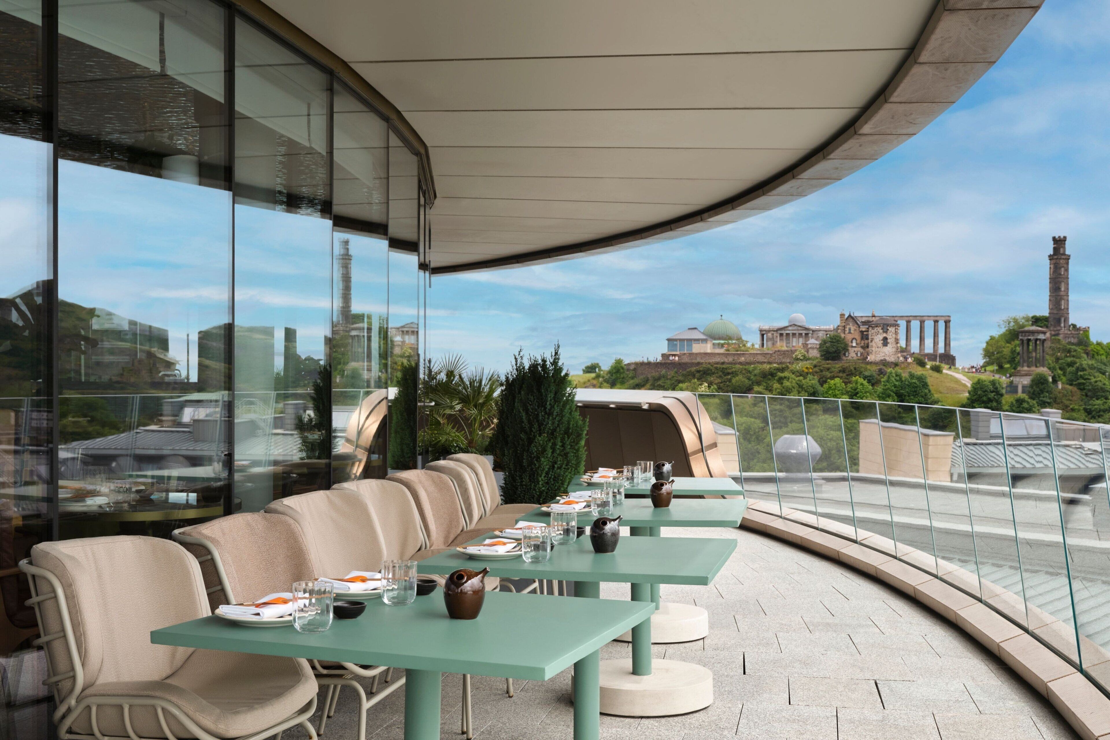 An outdoor dining area with tables and chairs, overlooking a historic building and a tower.