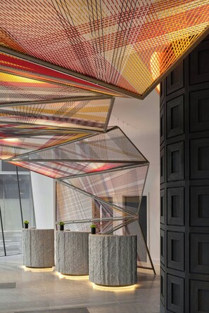 A modern interior with geometric ceiling structures and stone bases.