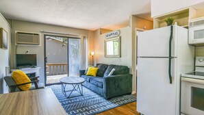 A compact living space with a sofa, a dining table, a TV, a refrigerator, and a microwave. - Lakefront Escape w/ Boat Slip on Table Rock Lake! (Kimberling City)