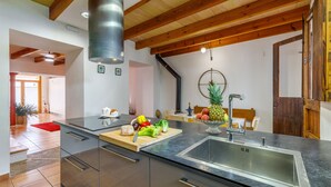 A modern kitchen with a central island, stainless steel appliances, and wooden beams on the ceiling.